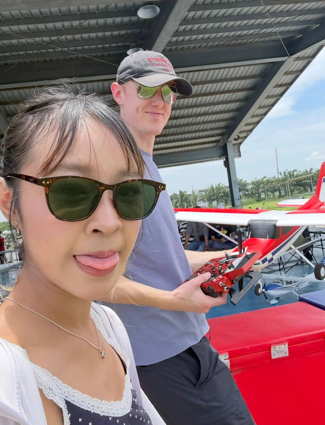 At an RC flying field with a friend, holding a transmitter beside a model aircraft